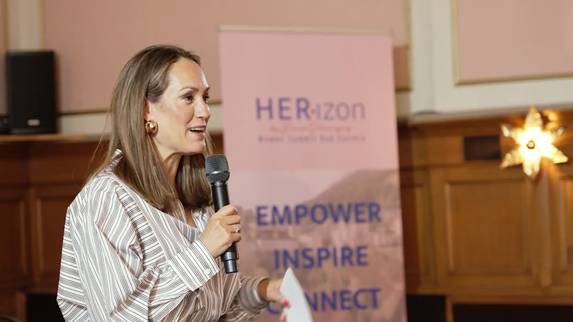 Speakerin am Mikrofon vor dem HER•izon-Banner beim Summit 2026